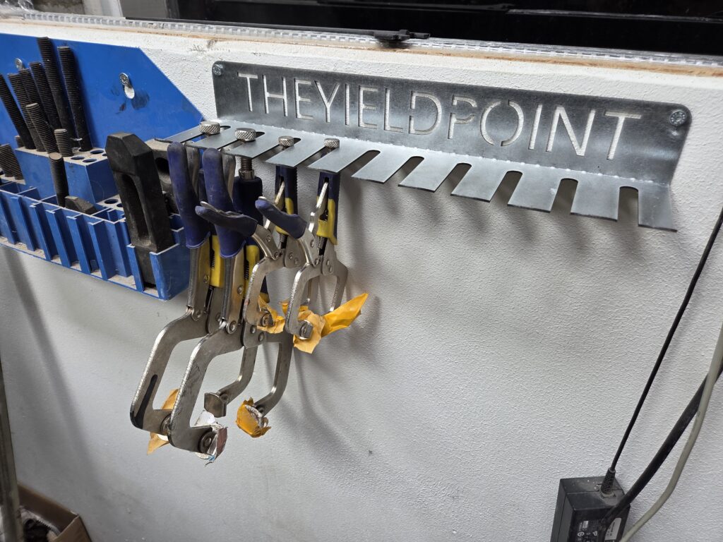 Laser-cut steel The Yield Point sign built into a welding clamp rack in the workshop