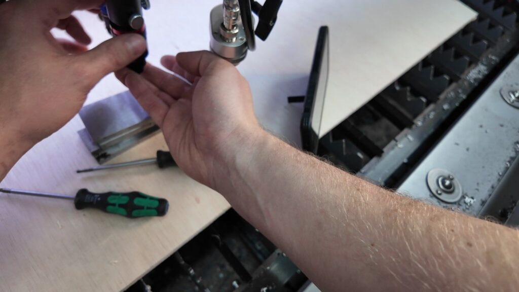 Realigning the GWEIKE M3 Ultra laser head with a screwdriver after it hit the plywood