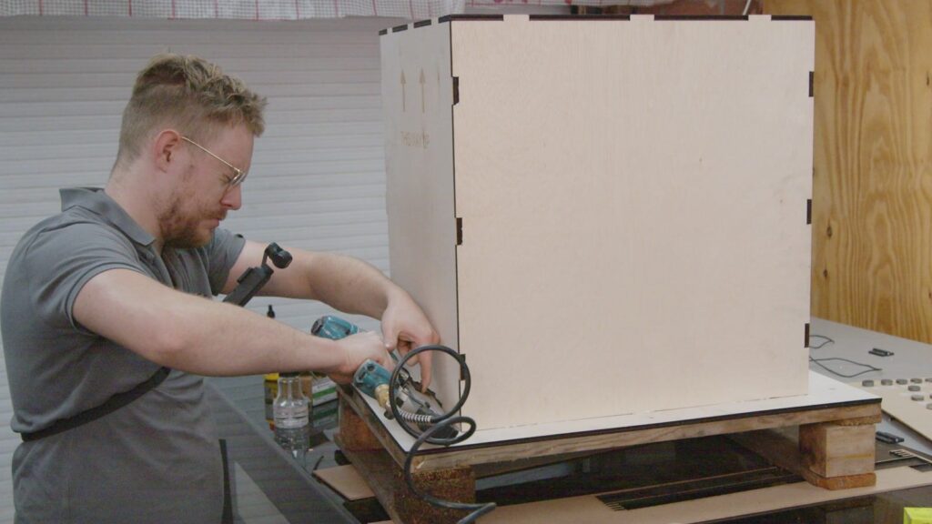 Assembling the laser-cut plywood shipping crate with a nail gun