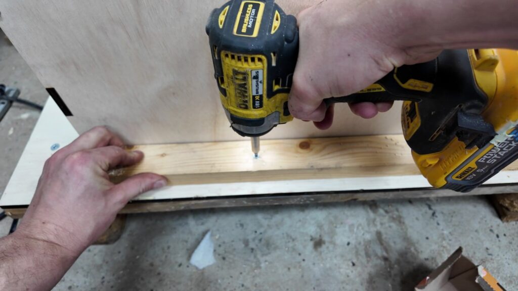 Screwing a wooden brace into the crate to stop the chiller moving